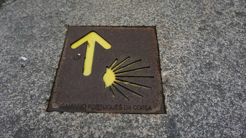 Stone marking on the Camino de Santiago with yellow arrow and shell, pilgrimage on the Caminho