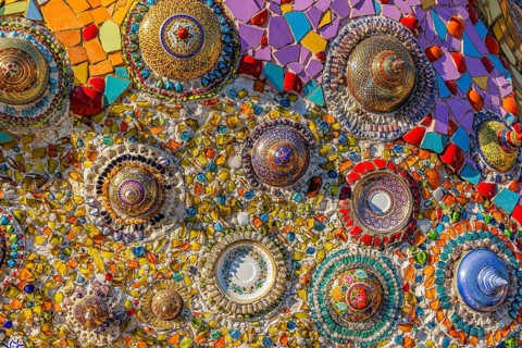 A wall decorated with colorful mosaic tiles and glass works of art, Buddhist temple complex Wat