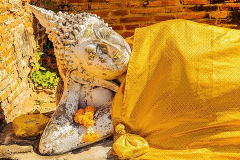 Reclining stone Buddha statue covered with yellow cloth, historic Buddhist temple complex,