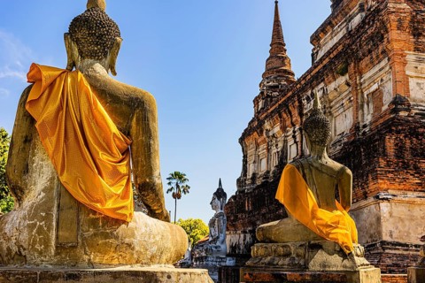 Stone Buddha statues decorated with yellow cloths, historic Buddhist temple complex, Ayutthaya,