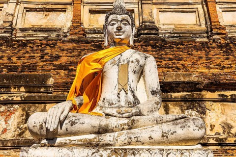 Stone Buddha statue decorated with yellow cloth, historic Buddhist temple complex, Ayutthaya,