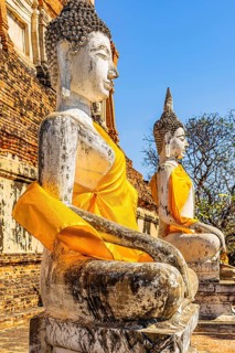 Stone Buddha statues decorated with yellow cloths, historic Buddhist temple complex, Ayutthaya,