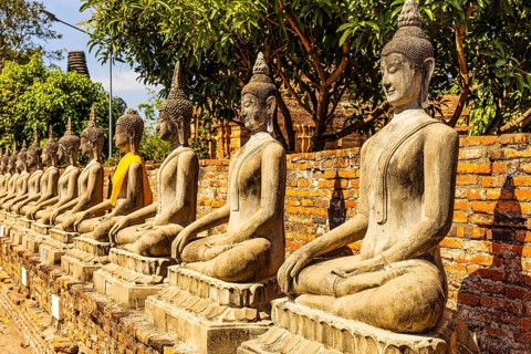Stone Buddha statues sitting in a row, historic Buddhist temple complex, Ayutthaya, Thailand