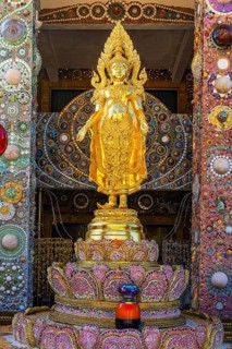 Gilded standing Buddha statue on a base decorated with mosaics and glass works of art, Buddhist