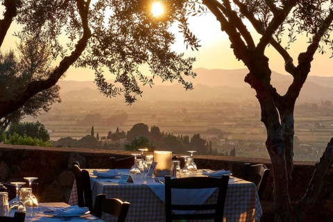 A set table under trees with a view of a vast landscape at sunset, Hotel Europa, garden restaurant