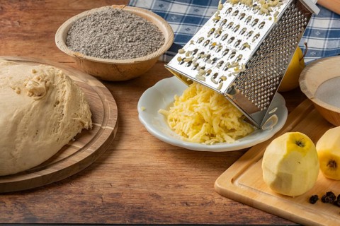 Grated apples and poppy seeds next to dough on rustic table