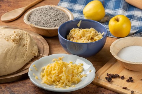 Grated apples in a bowl, dough, poppy seeds and sugar for baking preparation on the table