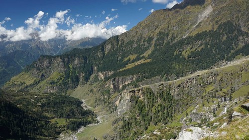 Valleys and densely wooded slopes on the Manali-Leh Highway under clear, sunny skies, trekking