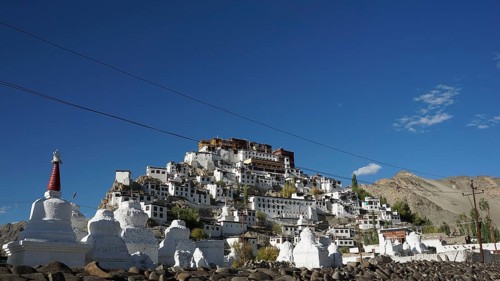 The sprawling Thiksey Buddhist monastery with several stupas against a mountain backdrop under a
