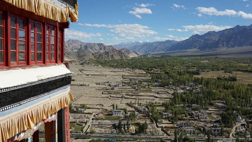 View from a Buddhist monastery of a settlement and vast mountain landscape under blue sky, trekking