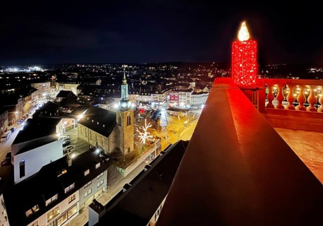 Large candle sculpture for Advent on the town hall tower in the evening with a view of St. John's