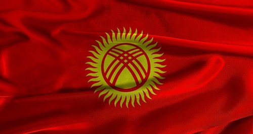 Flag of Kyrgyzstan with fabric textured background. Close up of National flag of Kyrgyzstan with