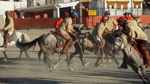 Group of polo players in traditional clothing playing polo on a clay court in Leh, dynamic scene,