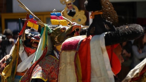 People wearing traditional masks and colorful costumes in a cultural ceremony in Leh, trekking in