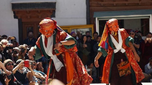 Two dancers in colorful costumes perform a traditional dance in front of an audience, Leh, Trekking