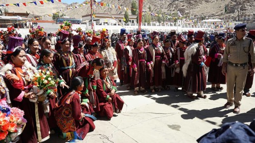 A large group in traditional costume gathers during a cultural festival in Leh, some carrying