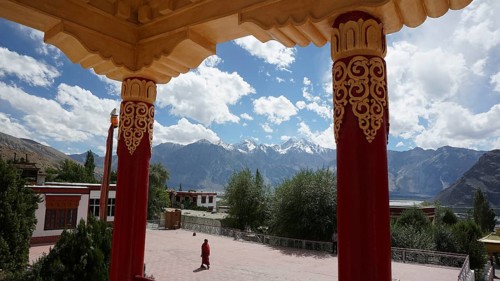 View across the courtyard of a Buddhist monastery to mountains surrounded by colorful, decorated