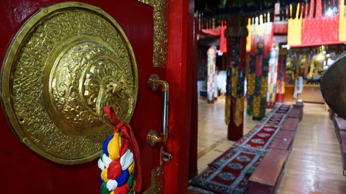 View through the imposing door, magnificent interior of a Buddhist temple with red carpets and