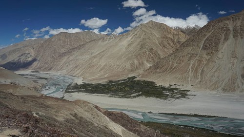 Extensive Nubra Valley with river course and impressive mountains under sunny skies, trekking in
