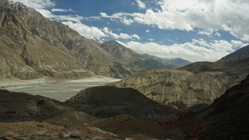 Wide mountain landscape under a cloudy sky with rocky slopes and a valley, trekking in Ladakh,