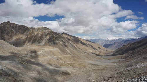 Wide mountain landscape with winding mountain road under a cloudy sky, trekking in Ladakh,