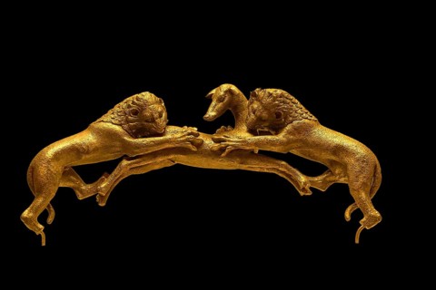 Two golden lions attacking a deer on a dark background, handle of a bronze vessel, Olympia