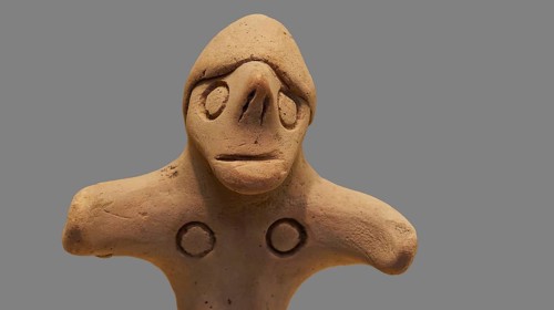 Anthropomorphic votive statuette, delicate clay sculpture with simple facial features on a light