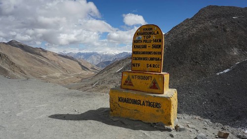 Signpost on dusty Khardung-la Pass in the mountains with sweeping views of surrounding mountains