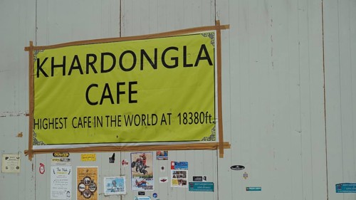Sign of a cafe at Khardungla Pass on a high mountain road with various stickers, trekking in