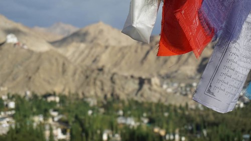 Close-up of prayer flags in foreground with mountain landscape in background under cloudy sky,