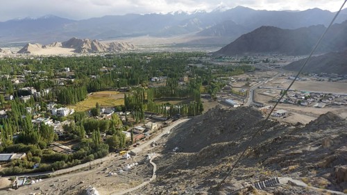 Extensive mountain and valley landscape with green trees and cloudy sky, trekking in Ladakh,