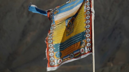 Colourful Tibetan prayer flag moving in the wind in front of a rocky mountain, trekking in Ladakh,
