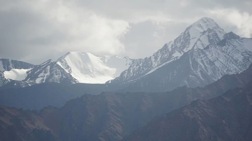 Snowy mountain peaks rise majestically under a cloudy sky, trekking in Ladakh, Himalayas, India