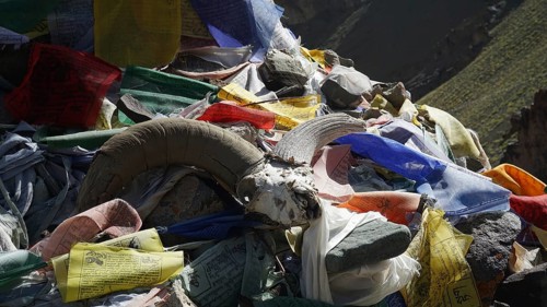 Close-up of prayer flags and a goat horn on a pile of stones, trekking at Stok La Pass in Ladakh,