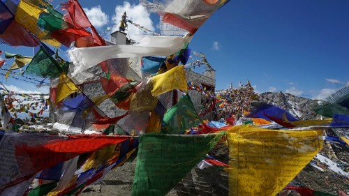 Close-up, colorful prayer flags waving in the wind in front of a temple at Khardung-La Pass in the