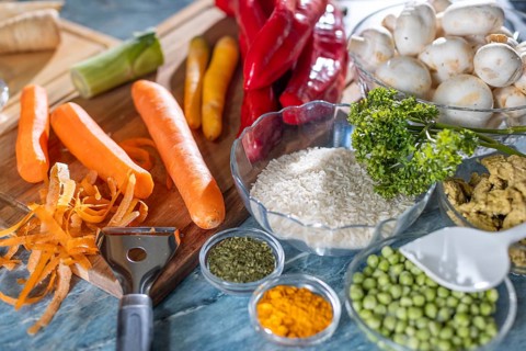 Fresh ingredients and spices such as peppers, peas, rice, mushrooms and peeled carrots