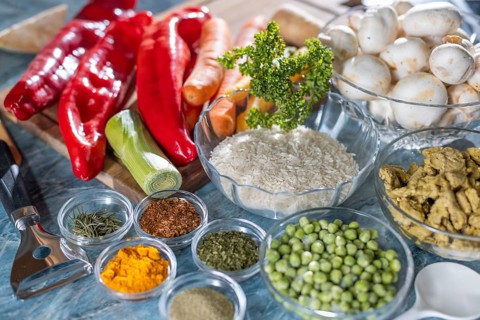 Various fresh ingredients and spices such as peppers, peas, rice, mushrooms and carrots