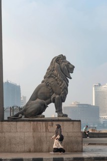 Cairo, Egypt. July 1st 2024 A woman walks past one of the famous bronze lions guarding Qasr El Nil