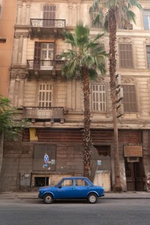 Cairo, Egypt. July 1st2024 A small blue car parked in an empty street of Downtown Cairo, with palm