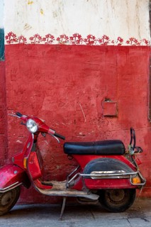 Cairo, Egypt. November 26th 2022 Cute red motor scooter parked against a red painted wall in the