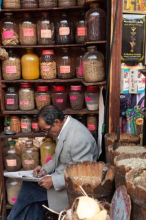 Cairo, Egypt. December 7th 2022 An Egyptian man doing a crossword while sitting in a spice shop in