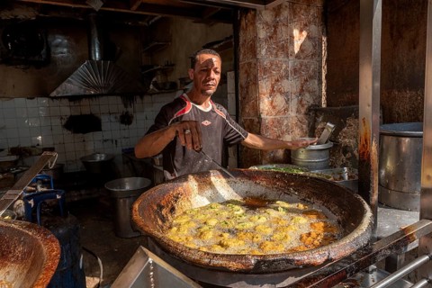 Cairo, Egypt. November 26th 2022 An Egyptian man deep frying Falafel, a chickpea and herb filled