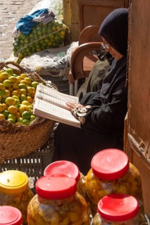 Cairo, Egypt. December 7th 2022 An Egyptian woman reading a book while selling fruit and vegetables