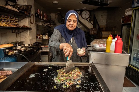 Cairo, Egypt. November 30th 2022 An Egyptian woman frying hot green peppers and chopped liver to