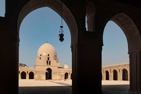 Silhouetted arches of the interior architecture and courtyard showing the dome of Ibn Tulin Mosque