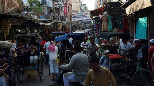 Bustling street scene with bicycle rickshaws and people in a busy market, Delhi, India