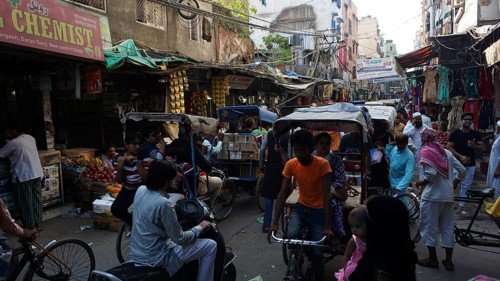 Bustling market street full of bicycle rickshaws and people in an urban area, Delhi, India