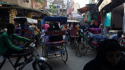 Lively urban street scene with bicycle rickshaws and hustle and bustle at a market, Delhi, India