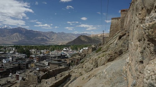 View of Leh on the mountainside with a stone wall and clouds in the sky, view from Leh Palace to