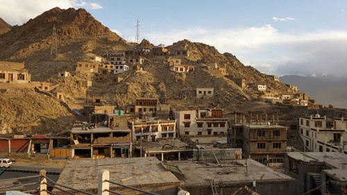 Mountain settlement with buildings built close together and rocky slopes under clear skies, Leh,